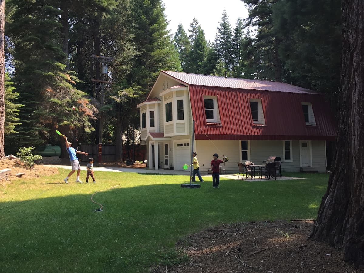 Exterior of the Carriage House with a large grassy yard and children playing