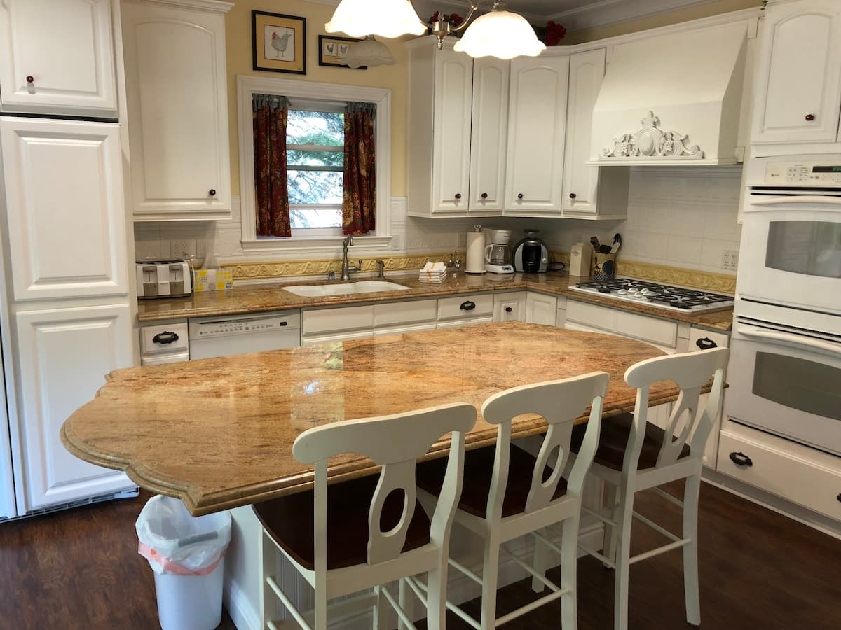 Kitchen with granite island, white cabinets, and bar stools