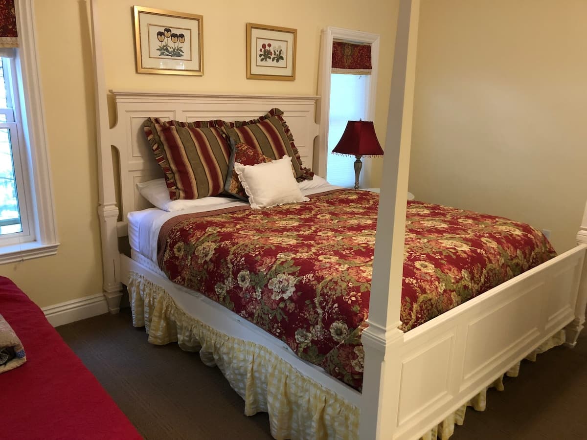White four-poster bed with floral bedding in one bedroom suite