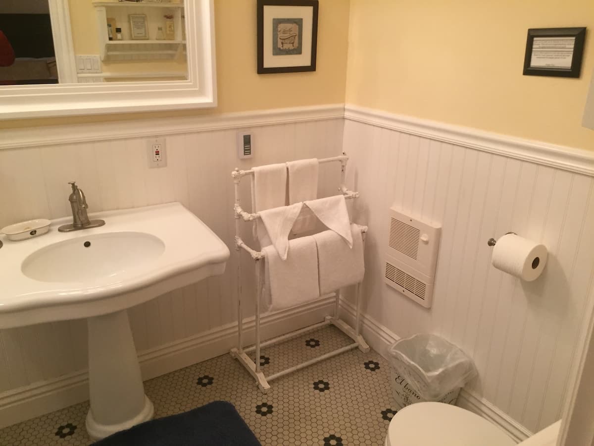 Bathroom with pedestal sink, towel rack, and vintage tile floor