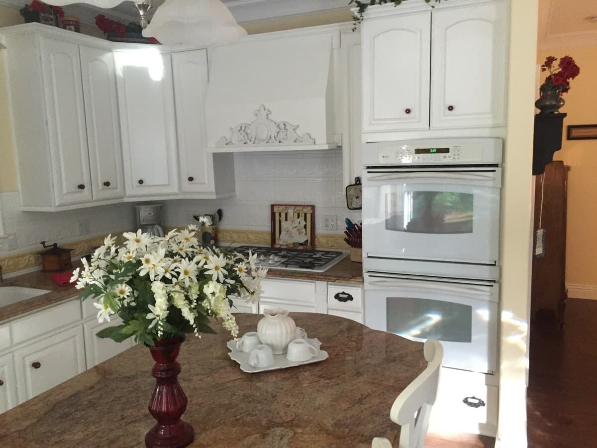 Kitchen angle with double wall oven, cooktop, and island flowers