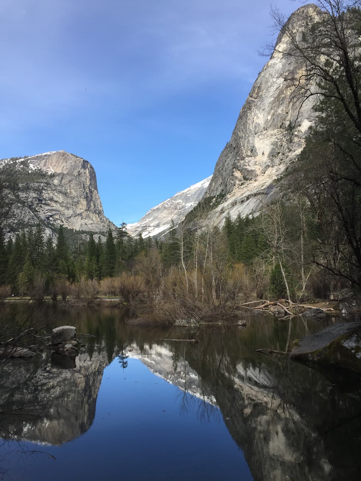 Still water reflecting granite cliffs and trees in Yosemite