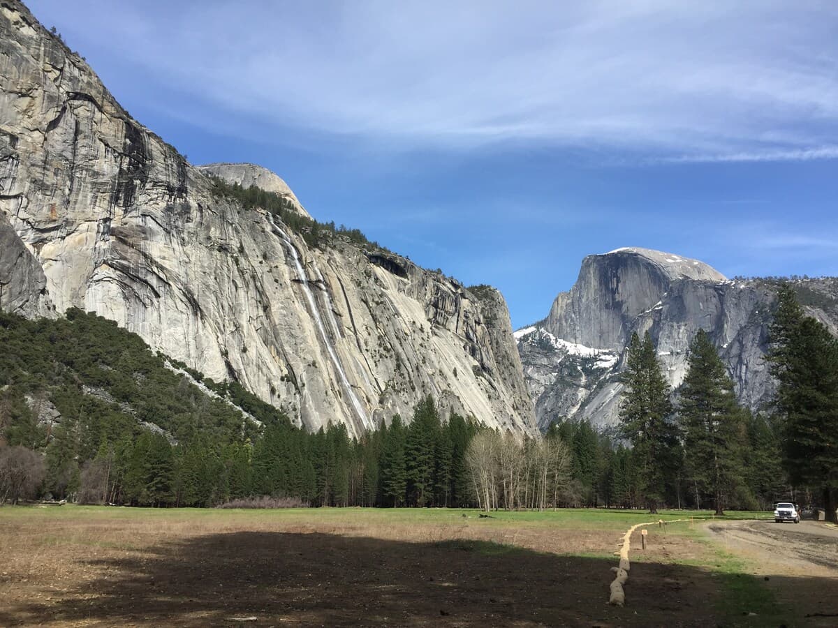 Wide Yosemite valley meadow with granite cliffs in the distance